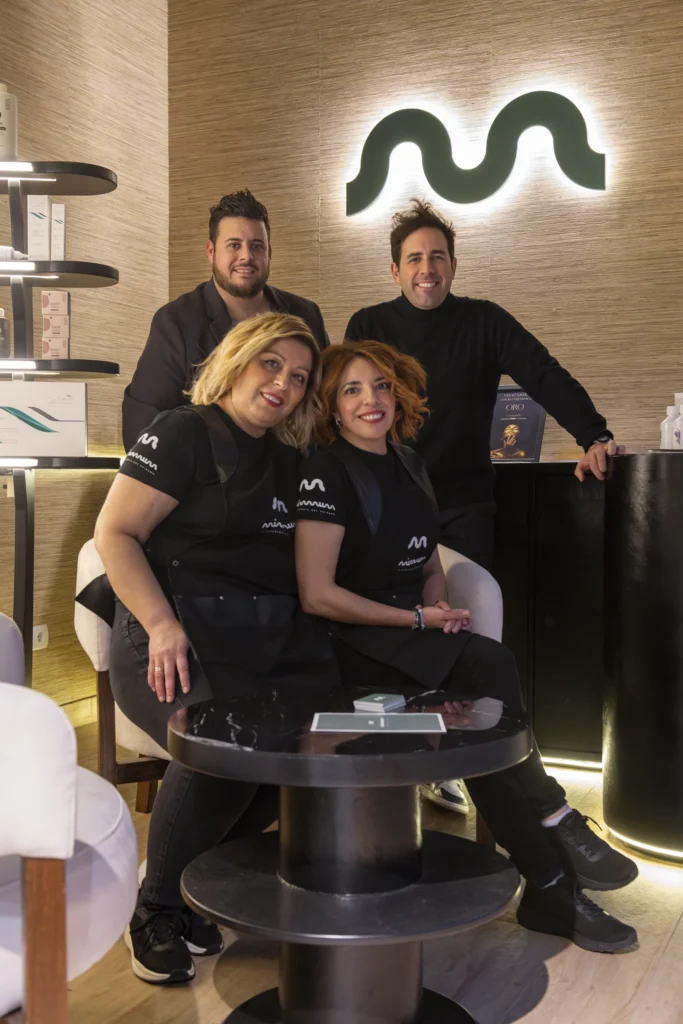 Equipo del salón MIMMUM con el símbolo retroiluminado al fondo, diseñado por Creatias Estudio