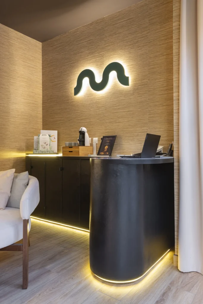 Mostrador de MIMMUM con el símbolo retroiluminado en la pared, interiorismo de Carlos Roma, diseñado por Creatias Estudio