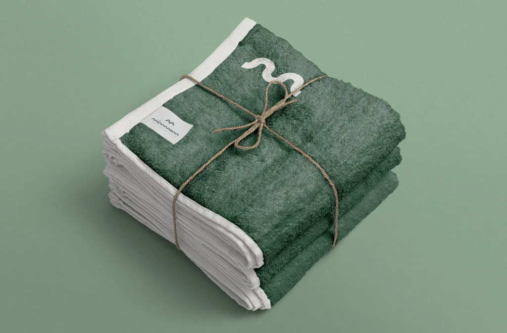 Toallas verdes de MIMMUM con el símbolo bordado y etiqueta de marca, diseñado por Creatias Estudio