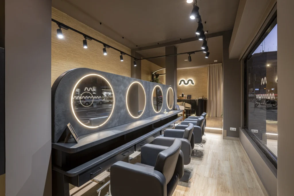 Zona de peluquería de MIMMUM con espejos circulares iluminados, interiorismo de Carlos Roma, diseñado por Creatias Estudio